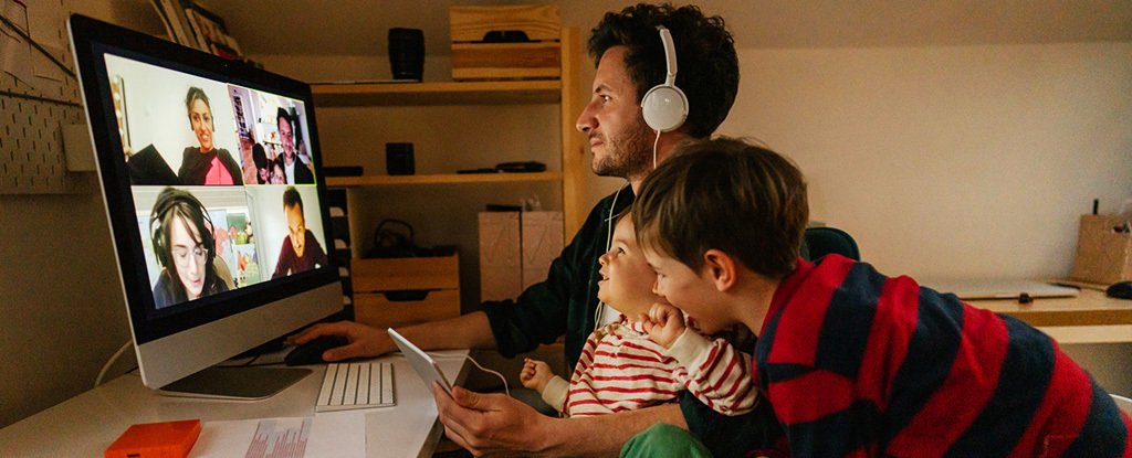 Two children interrupt an adult who is taking a video conferencing call in his home office.